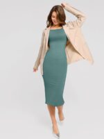 Vrouw in groene jurk met blazer.