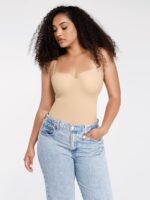 Vrouw in beige bodysuit als top met high-waisted jeans.